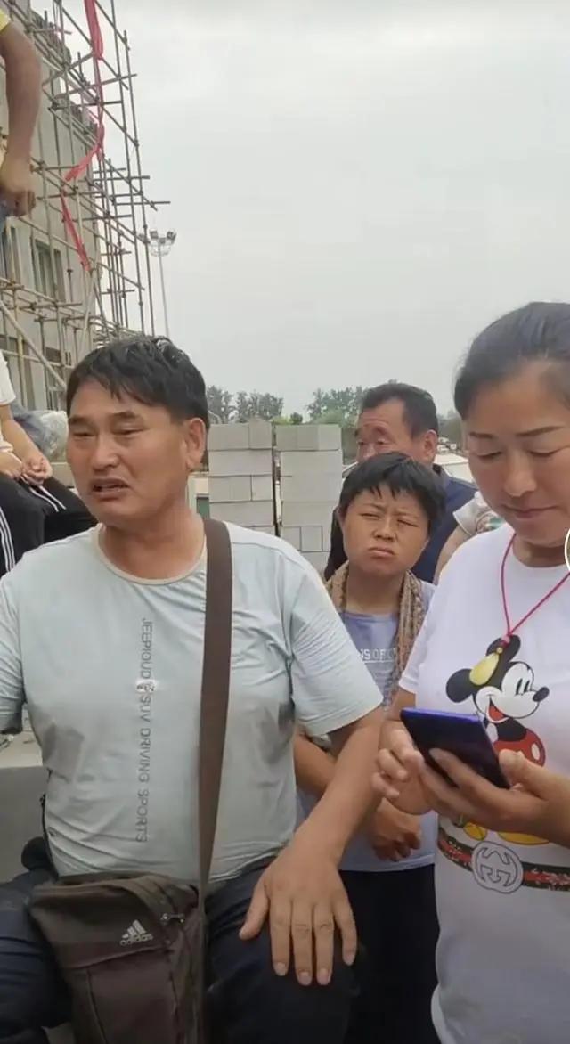 大衣哥耐心教村民唱歌 身后未建成小楼抢镜 唱歌干活两不误