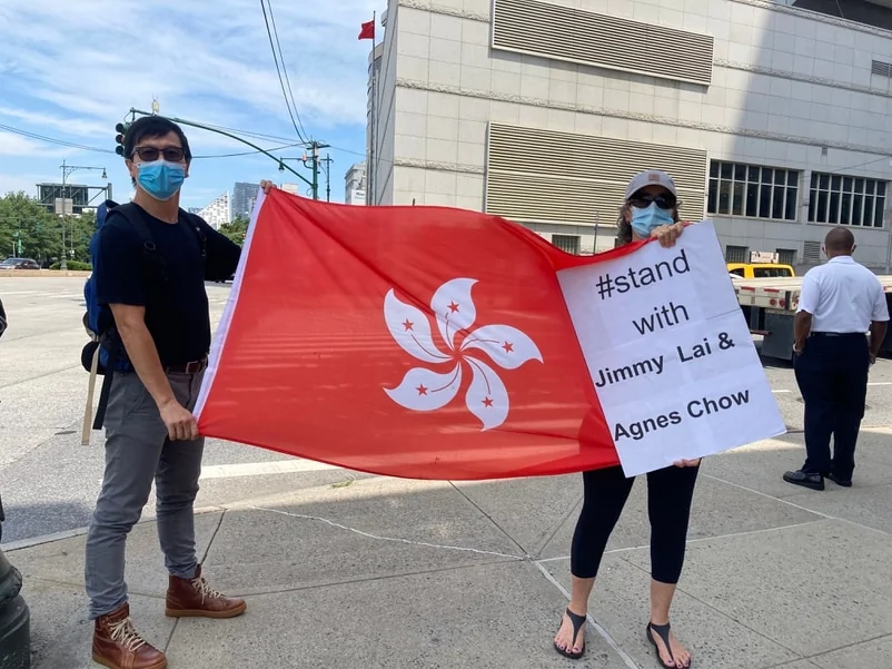 NICOLE在中國駐紐約領事館對面舉起香港區旗及「與黎智英及周庭同行」的標語。
