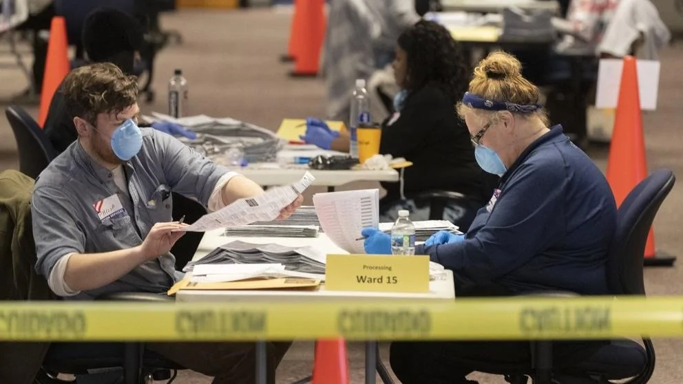 图为工作人员在威斯康星州的一处投票点处理邮寄选票。（AP）