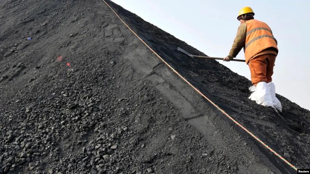 一名中國工人在山東日照港鏟着從澳大利亞進口的煤炭。（資料照片）