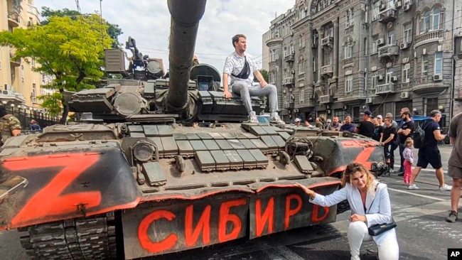 在这张从视频中拍摄的图像中，2023年6月24日，一名女子在停在俄罗斯顿河畔罗斯托夫一条街道上的一辆俄罗斯装甲车前摆出姿势拍照，车上写着“西伯利亚”。