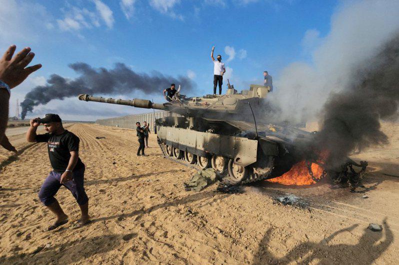 巴勒斯坦人在加薩圍欄旁站上一輛被摧毀的以色列坦克慶祝。(美聯社)