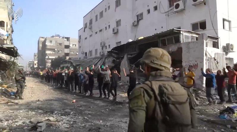 以色列军方14日公布影片，多名巴勒斯坦男性高举双手，在加萨北部阿德万医院附近列队...