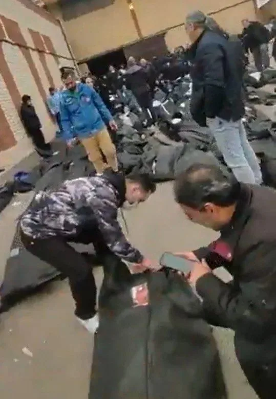 法医中心的停车场甚至外围街道上,密密麻麻地堆满了大量未及安葬的遗体,尸袋数量多到连路面都看不见。 图:翻摄X(前推特)