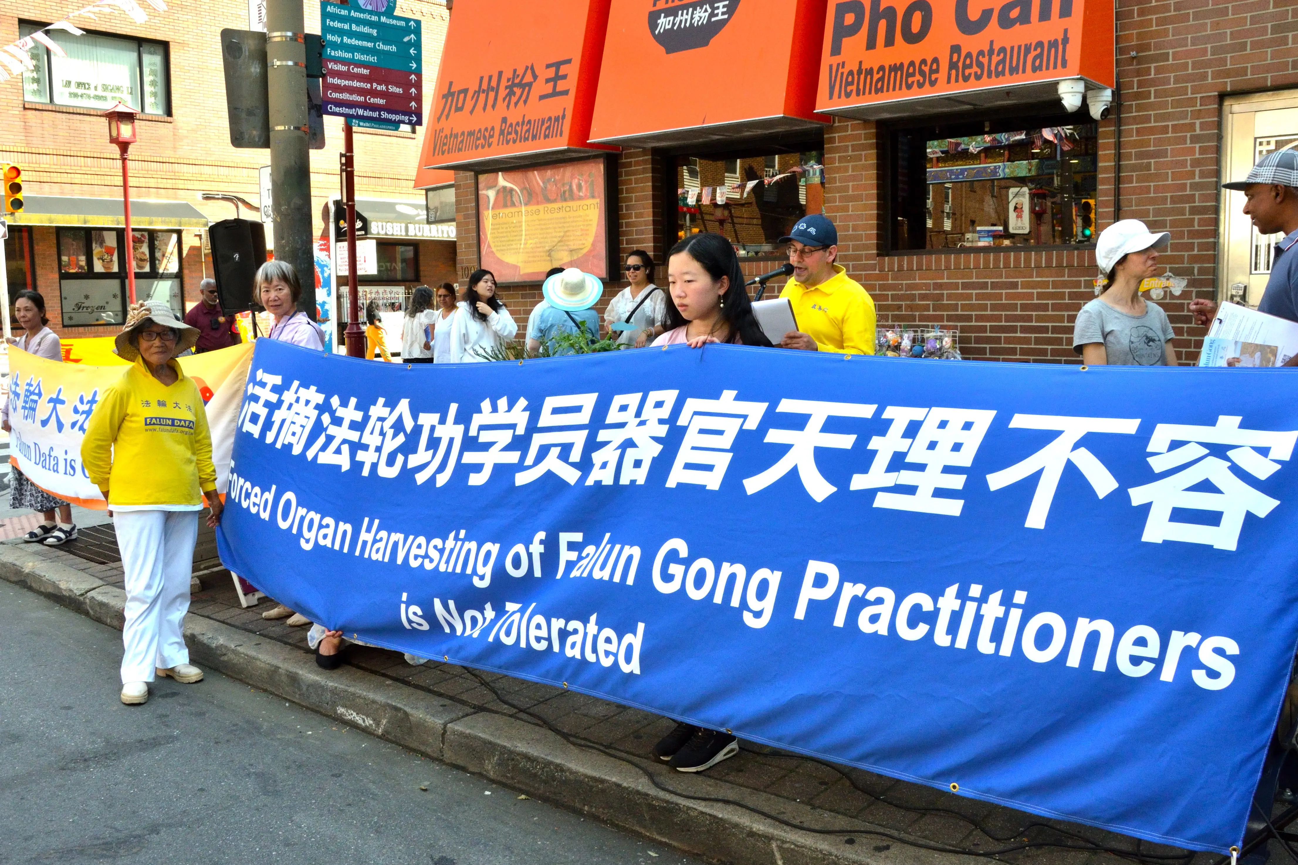 田忠鳳女士(橫幅前)在集會上講述了她在2006年3月在中共抓捕後險遭活摘器官的親身經歷。(良克霖/大紀元)