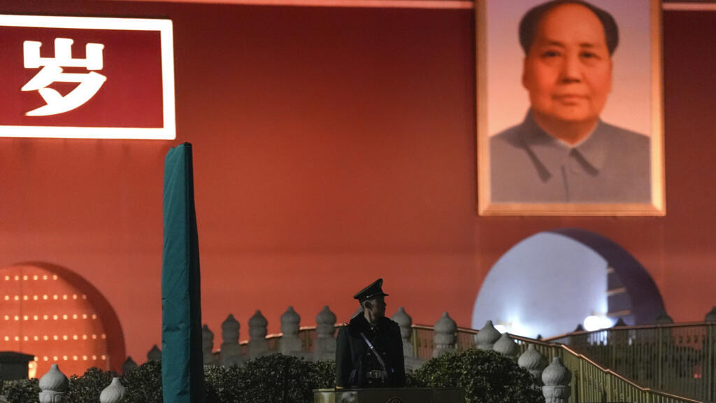 一名中国武警在天安门城楼上的毛泽东画像旁站岗。